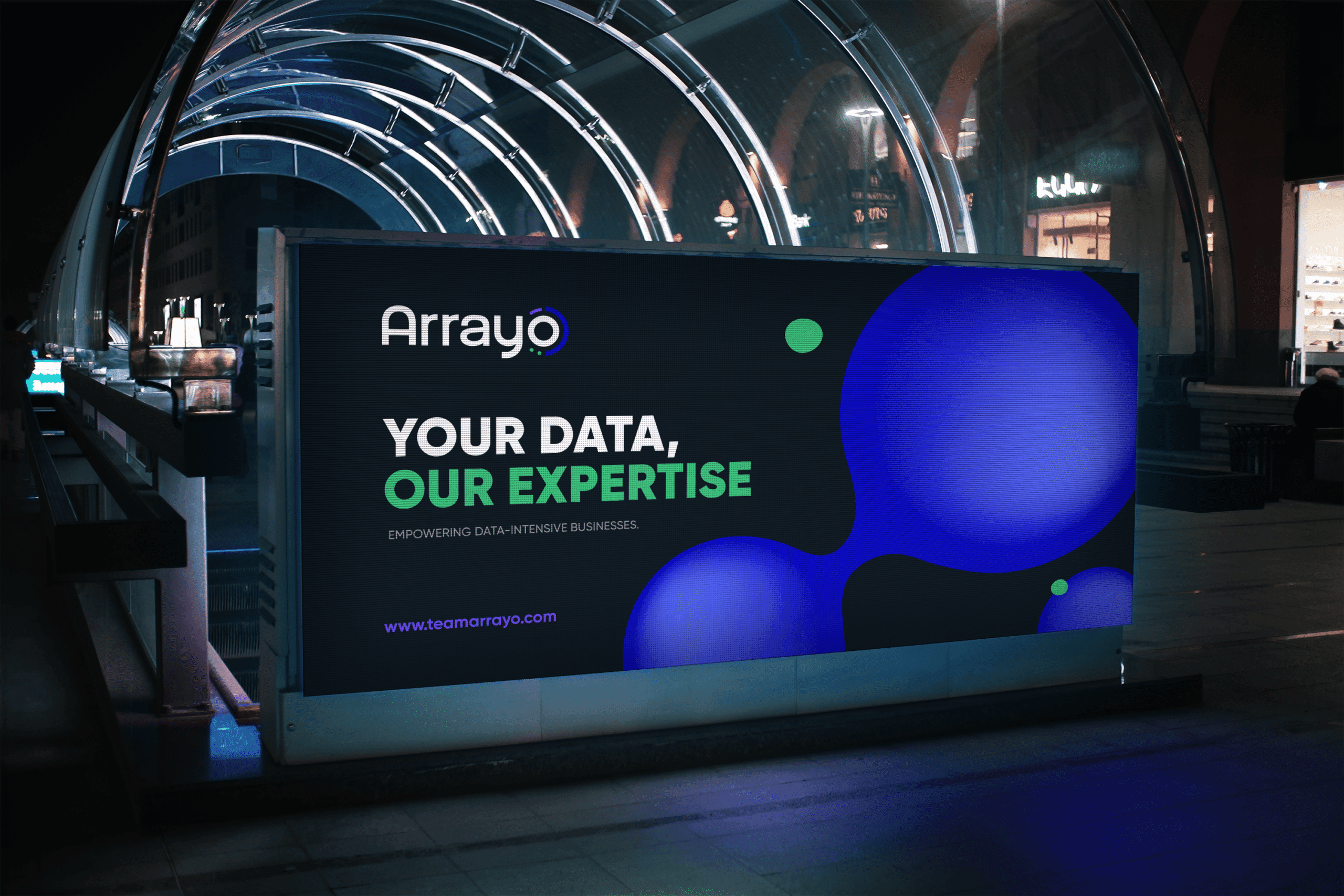 An illuminated Arrayo billboard in a station concourse reading “Your data, our expertise”